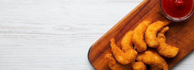 Fried shrimps tempura with sauce on wooden board over white wooden table, overhead view. Copy space.