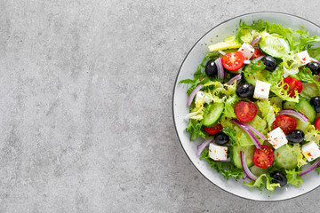 Vegetable salad with fresh cucumber, tomato, olive, onion, lettuce and feta cheese. Healthy food. Top view