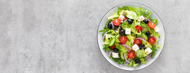 Abwaschbare Fototapete Vegetable salad with fresh cucumber, tomato, olive, onion, lettuce and feta cheese. Healthy food. Top view. Banner. © Sea Wave