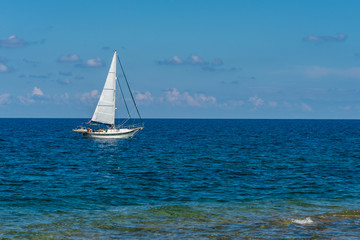 Fototapeta premium Close-up of a sailboat sailing at sea with a background of a blue sky.