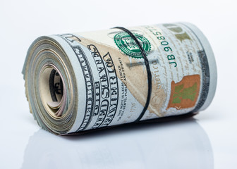 100 dollar bills twisted into tube and tied with an elastic band. white background.