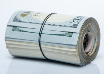 100 dollar bills twisted into tube and tied with an elastic band. white background.