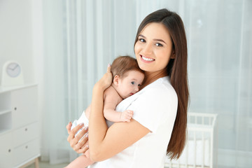 Obraz na płótnie Canvas Happy woman holding her baby in light nursery