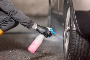 Professional car washer cleaning car alloy wheels .