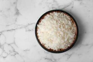Fototapeta na wymiar Bowl of boiled rice on marble background, top view with space for text