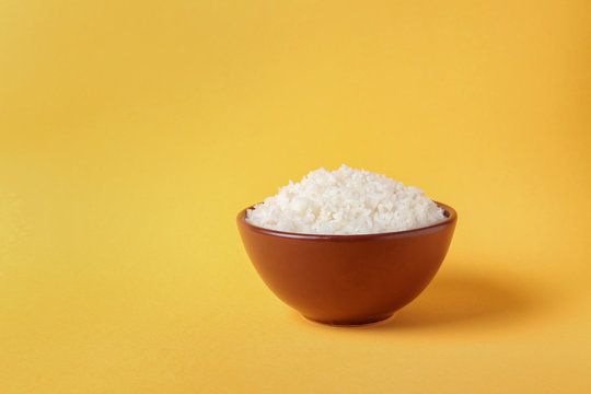 Bowl of boiled rice on color background. Space for text