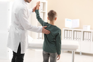 Chiropractor examining child with back pain in clinic