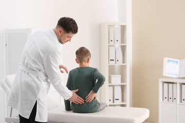 Chiropractor examining child with back pain in clinic