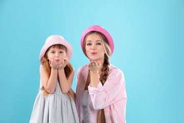 Happy woman and daughter in stylish clothes on color background