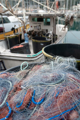 Close up on colored fishing nets. In the background a blurred fishing boat