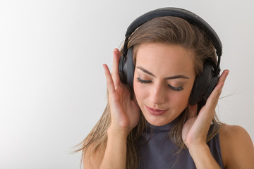 Woman with big headphones and listening to music on a white background