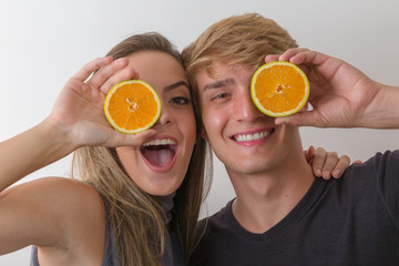 Beauty couple holding juicy orange slices on white background. Nutrition concept. Healthcare.