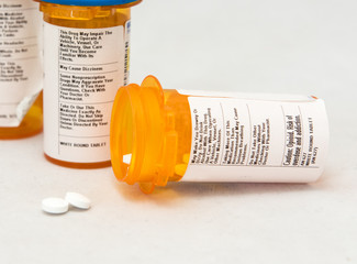 Opiod pill bottle and another pill bottle with pills spill out of the bottle.