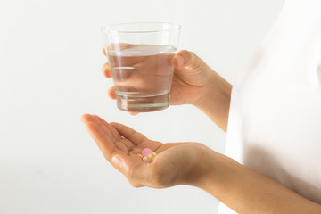 Closeup woman hand with pills medicine tablets and glass of water for headache treatment. Healthcare, medical supplements concept.