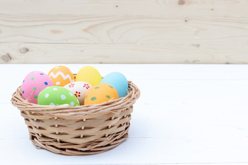 Happy Easter Day. Easter eggs concept. Closeup Colorful Easter eggs in nest and basket on white wooden background.
