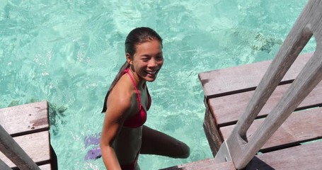 Sexy woman on vacation travel snorkeling swimming on beach looking at camera smiling happy wearing red bikini and pink snorkeling fins coming out of water