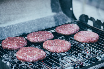 selective focus of uncooked fresh burger cutlets grilling on bbq grid