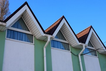 colored attic with windows under a tiled roof against a blue sky
