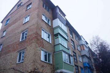 part of a brick brown house with a number of balconies and windows against the sky