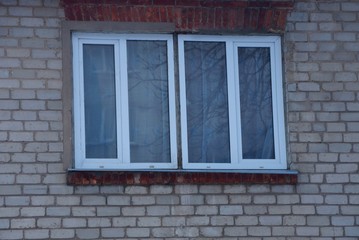 Fototapeta na wymiar two white plastic windows on a gray brick wall