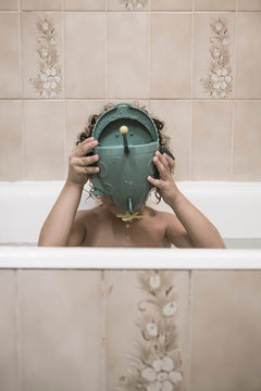 Enfant dans la baignoire se cachant derri&egrave;re son jouet