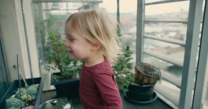 Little toddler playing on the balcony in city