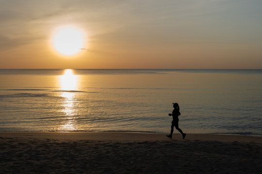 silhouette picture of running on the sand beach during sunrise. healthy and running sport concept