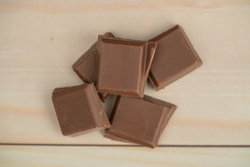Milk chocolate pieces isolated on background from top view
