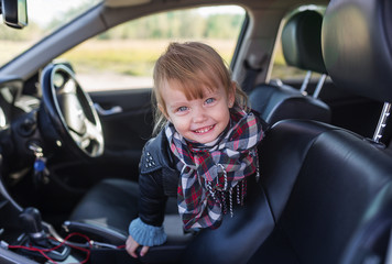 Portrait of little smiling girl in car inside.