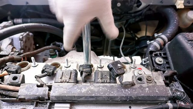 Timelapse - The car will not start, it's cold outside. A man unscrews a car engine spark plug.