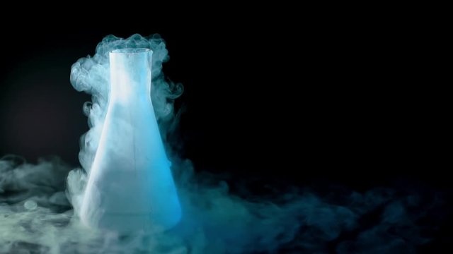 Flask with liquid nitrogen on black background. Concept of chemical experiments and tests. Edutainment. Copy space