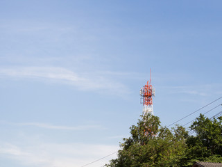 Telecommunication antenna tower with blue clear sky located in rural community.
