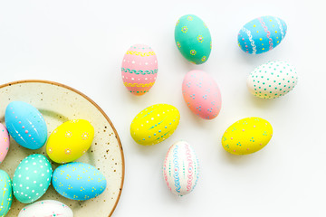 Festive Easter table. Colorful Easter eggs on plate on white background top view