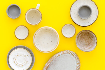 Kitchen concept. Crockery kit. Empty ceramic plates and mugs on yellow background top view