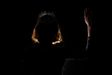Portrait Silhouette Shadow Back Rim Light of Miss Pageant Beauty Queen Contest Silver Diamond Crown wave hand express feeling smile, studio lighting dark black background, turn back head to camera © Jade