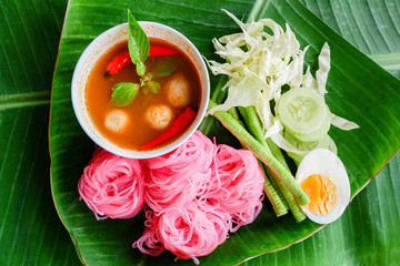 beautiful food noodle pink vermicelli and curry soup sauce with vegetable on banana leaf background