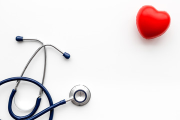 Heart health, health care concept. Stethoscope near rubber heart on white background top view copy space