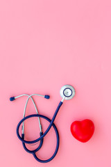 Heart health, health care concept. Stethoscope near rubber heart on pink background top view space...