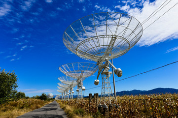 Array of satellite dishes or radio antennas against sky. Space o