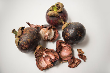 ripe peeled mangosteen and pieces of peel on a white background