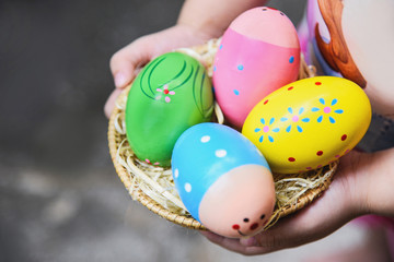 Fototapeta na wymiar Easter egg hunt colorful in basket on hand little girl / Egg painted in the nest
