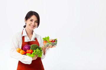 Asian young woman wearing an apron coat and holding fresh ingredients for healthy salad.
