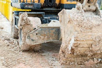 Fototapeta na wymiar Excavator is working into mud. close-up of large excavator bucket in mud. Part of the construction machine.