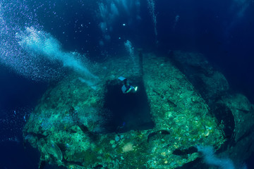 Free diver man dive to shipwreck in ocean, underwater