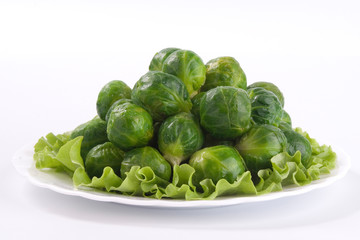 Close up of brussel sprouts in the white plate on white background