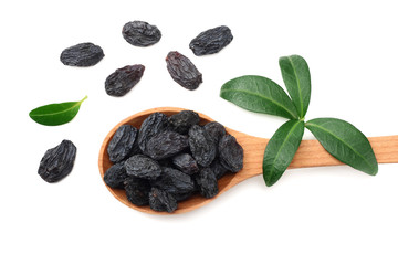 black raisins in wooden spoon with green leaves isolated on white background. top view