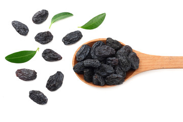 black raisins in wooden spoon with green leaves isolated on white background. top view