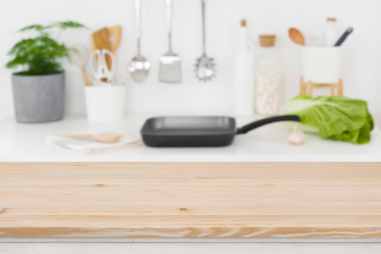 Defocused kitchen cooking place with empty wooden table in front