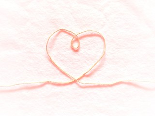 Heart shape made from hemp rope on softness cotton white background. A concept of love with light red color gradient.