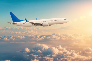 Verkehrsflugzeug fliegt über Wolkengebilde in dramatisch getöntem Sonnenuntergangslicht